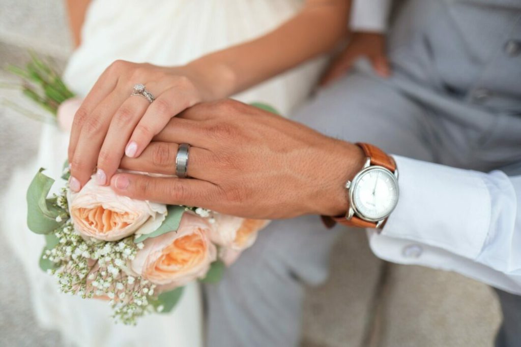 couples hands with wedding ring and flowers